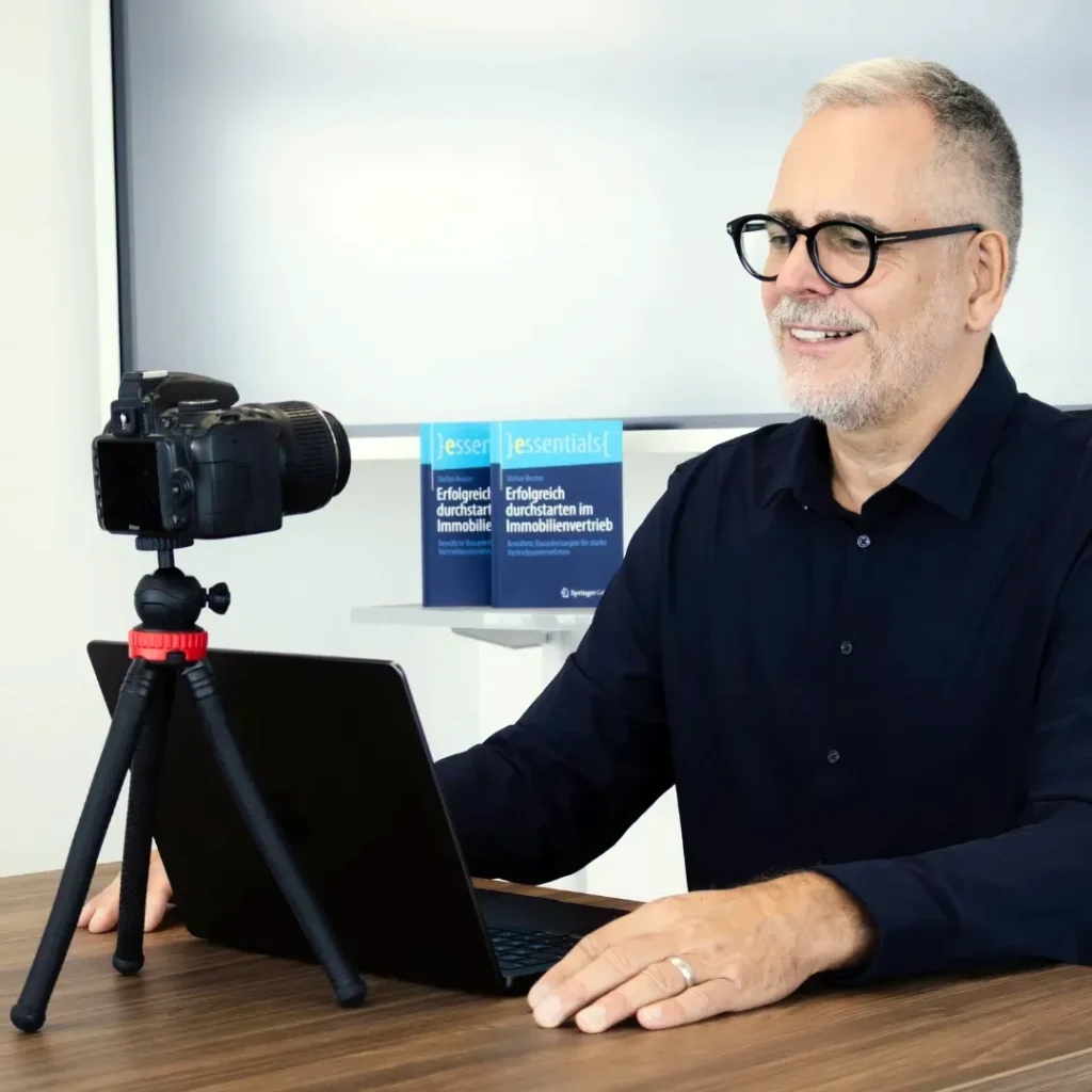 Stefan Reuter mit Laptop und Kamera am Schreibtisch