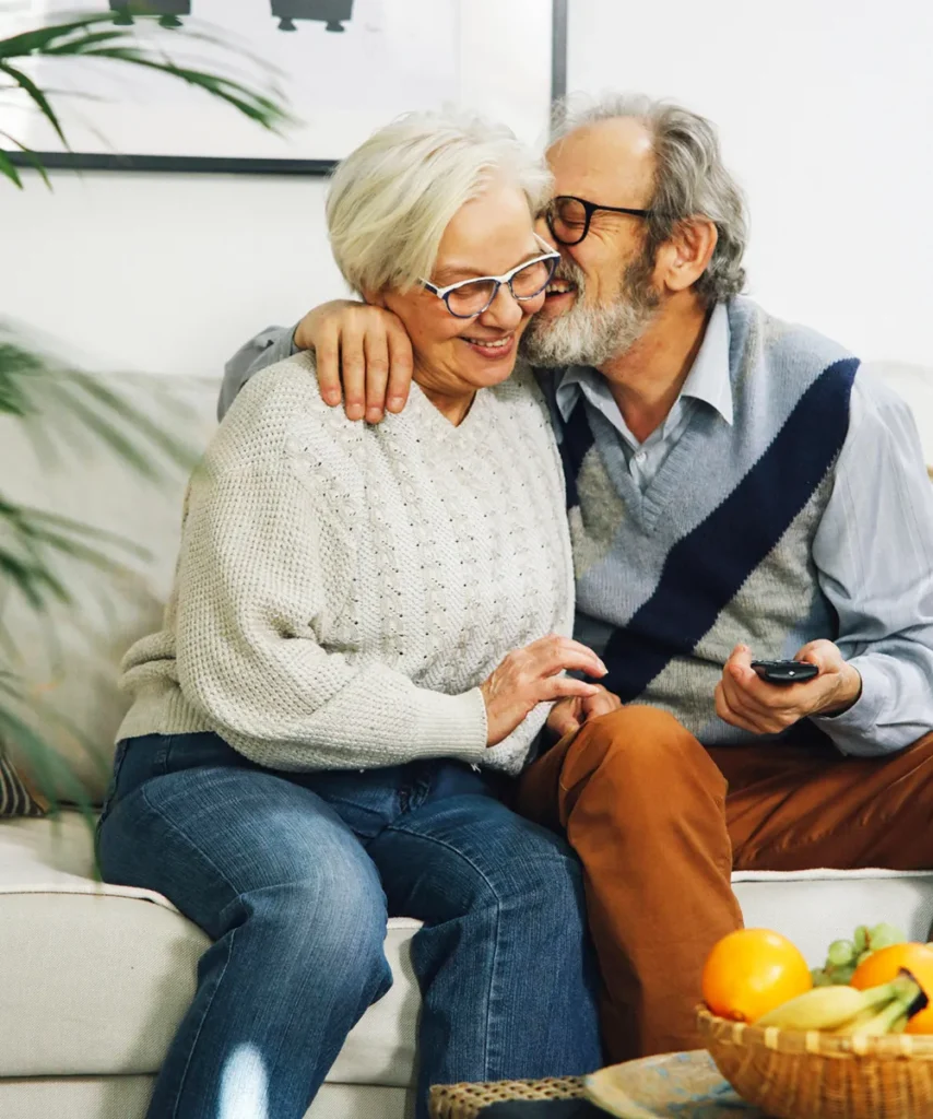 Ein lachendes Renterpaar sitzt auf einem Sofa