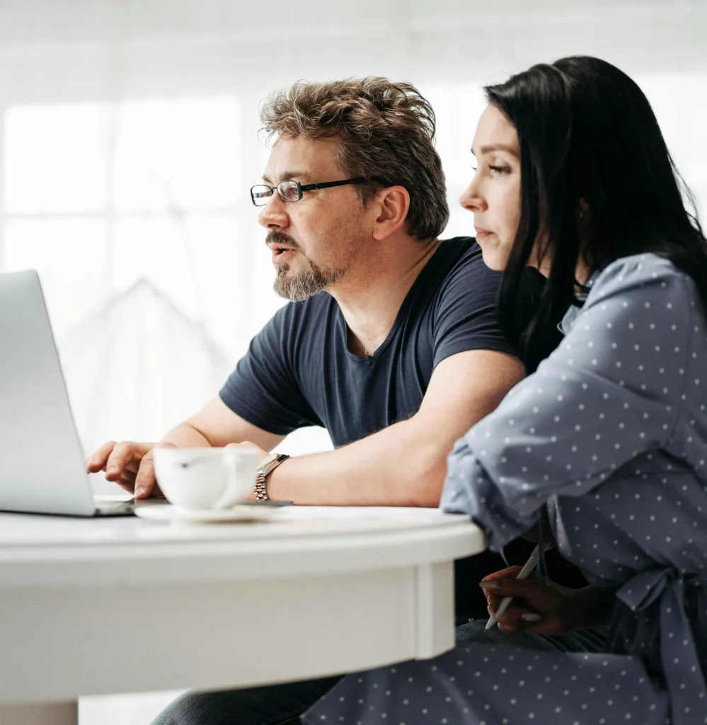 Ein Paar sitzt vor einem Laptop und informiert sich über Kapitalanlagen